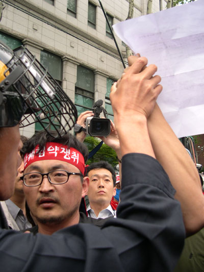 삼보일배를 하던 대오를 경찰이 가로막자 덤프연대의 한 간부가 집회신고서를 내보이며 항의하고 있다. 서울지방경찰청 명의로 되어있는 문서인데도 경찰은