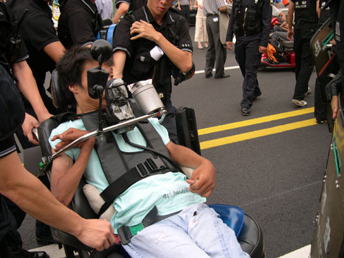 거리행진 중 대열을 막아선 경찰들이 한 참가자의 휠체어를 붙잡고 움직이지 못하게 하고 있다.