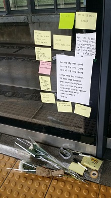지하철 2호선 구의역 스크린 도어 앞에 정비하던 하청노동자의 죽음을 애도하는 쪽지와 국화가 놓여있다.