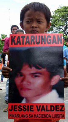 2004년 하시엔다 루이시따에서 살해된 희생자들의 2주년 추모식에서 희생자인 아버지의 사진을 들고 있는 아이<출처; www.arkibongbayan.org>